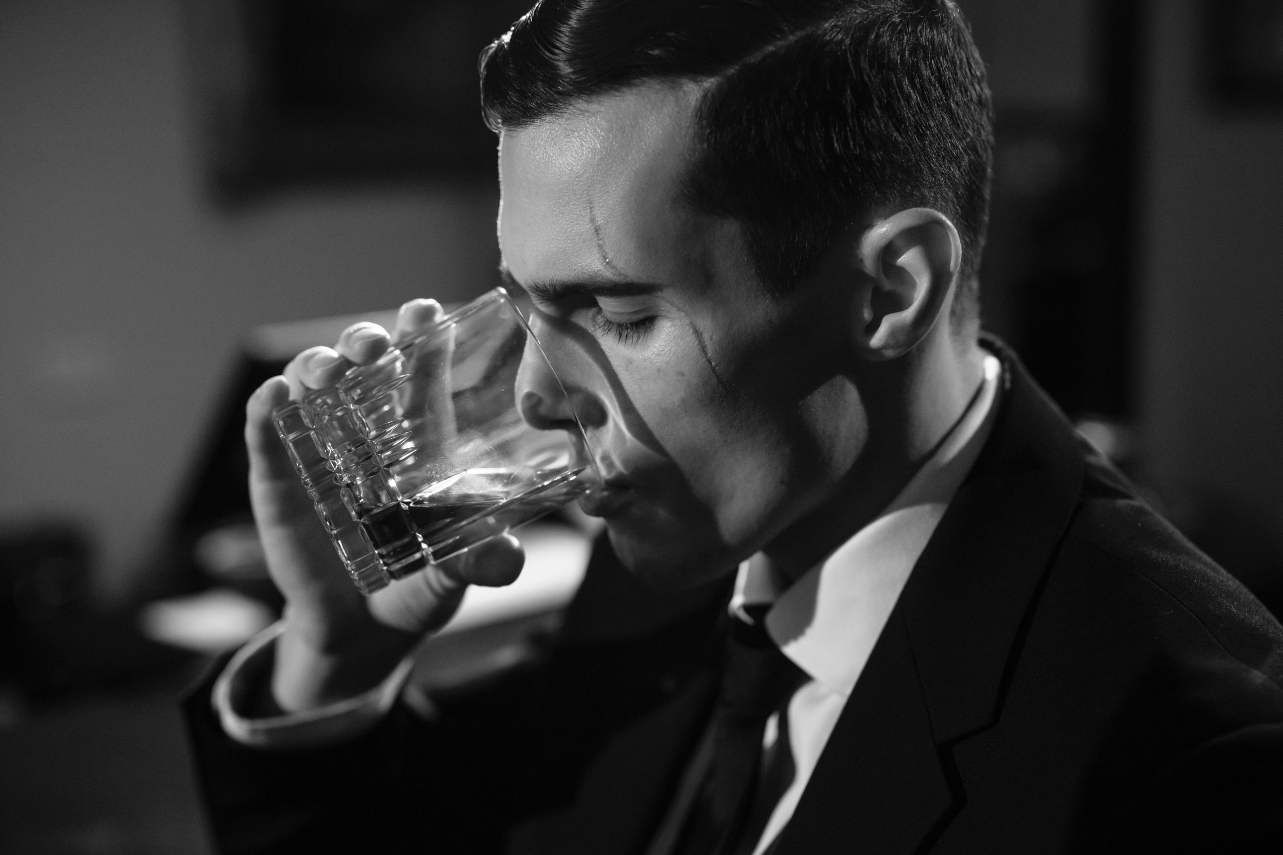 Homme en noir et blanc savourant un whisky film noir