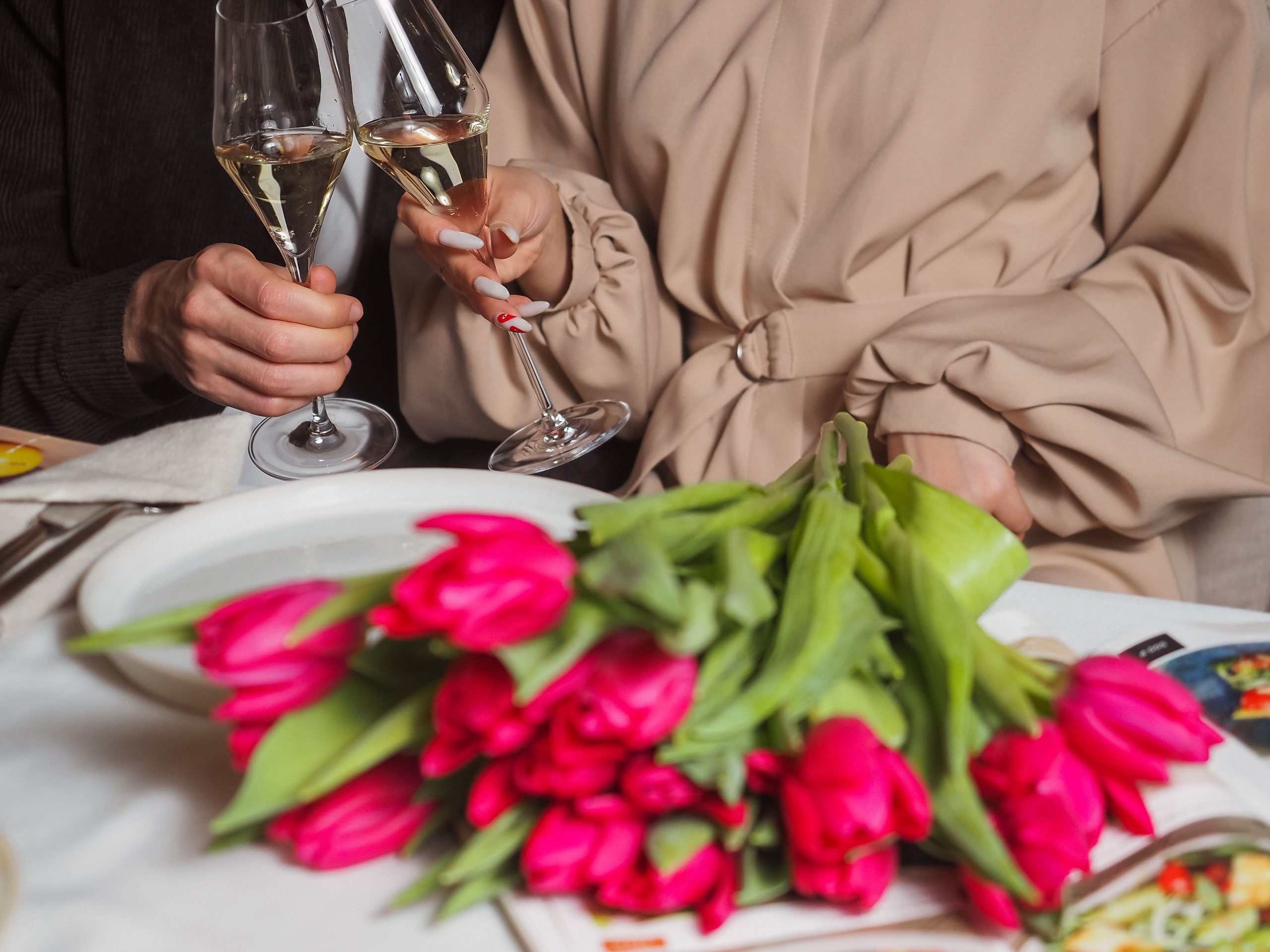 Couple trinquant avec tulipes roses sur table
