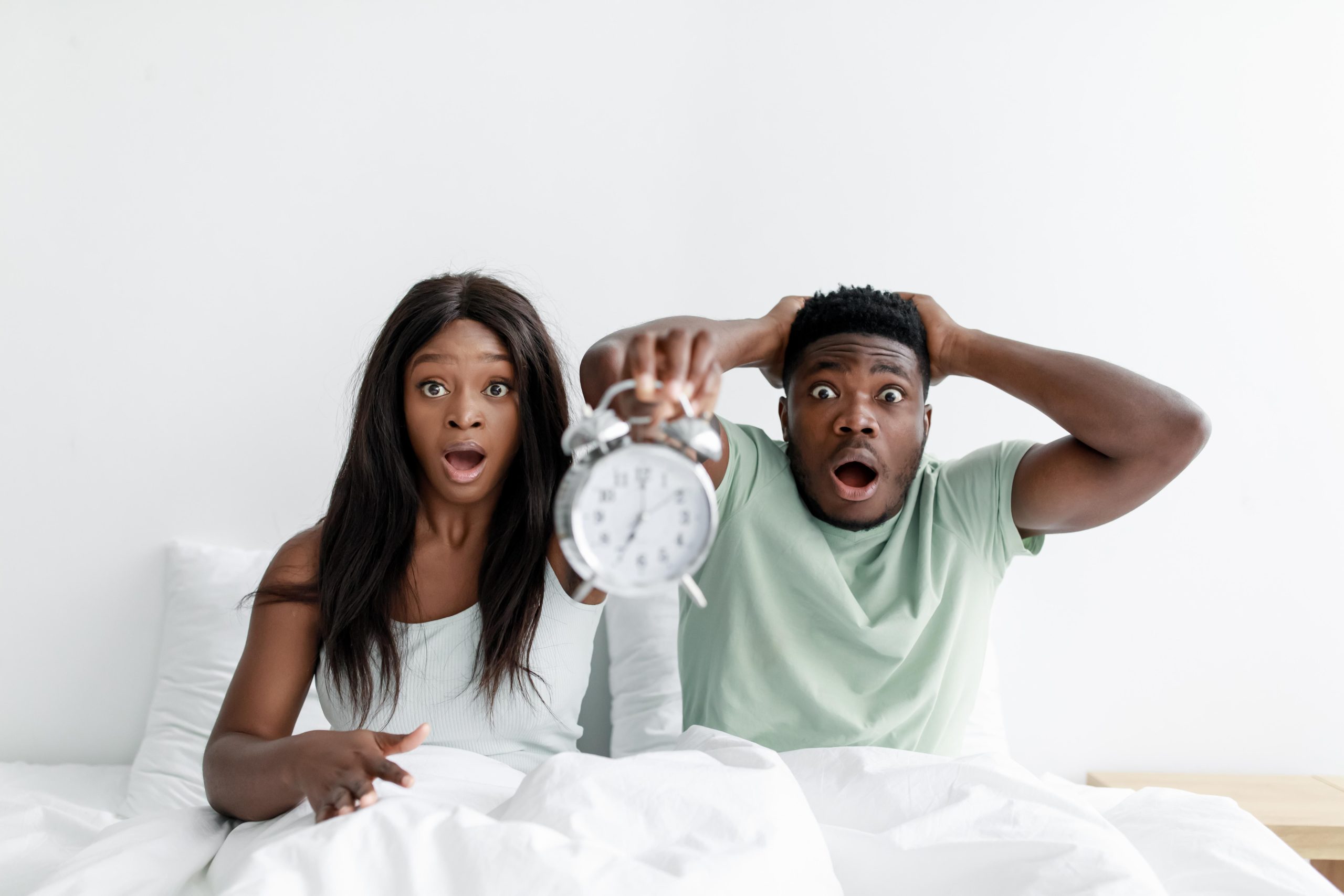 Couple surpris assis dans leur lit