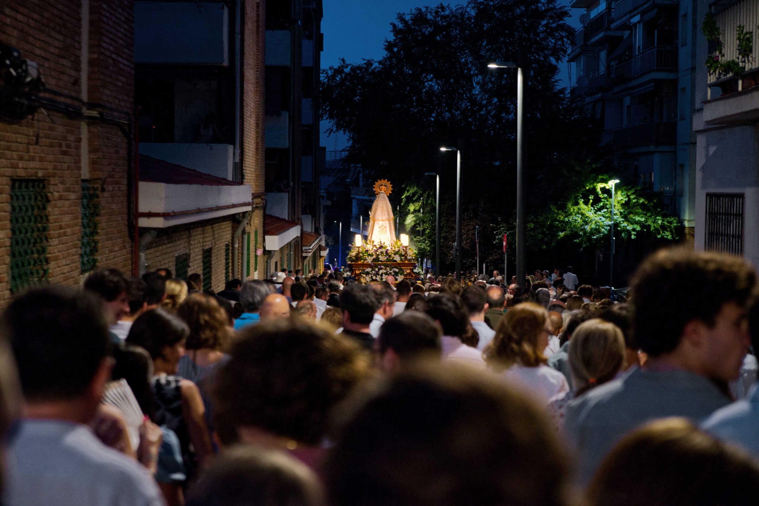 Procession nocturne urbaine avec figure religieuse et foule