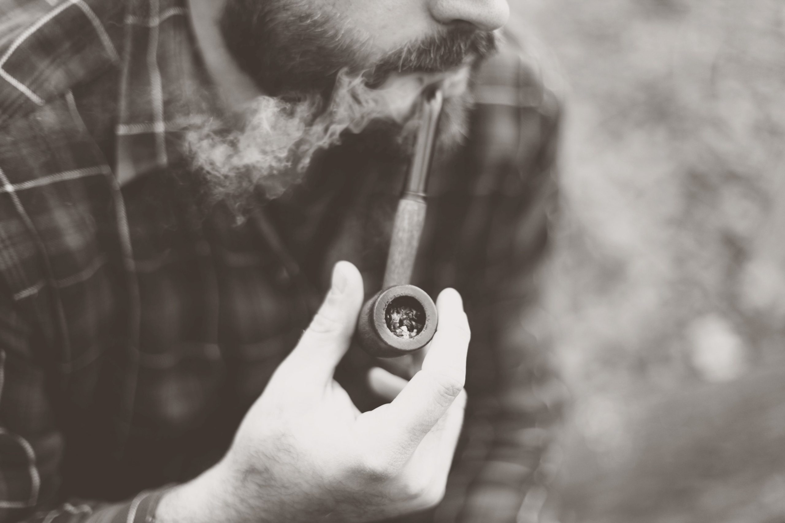 Homme barbu fumant la pipe en extérieur