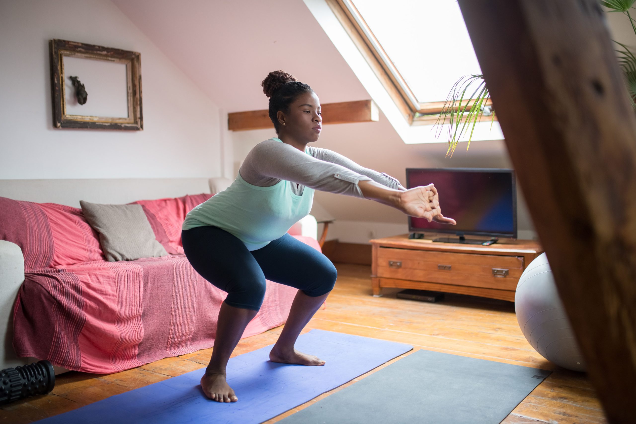Femme faisant des squats sur un tapis dans son salon