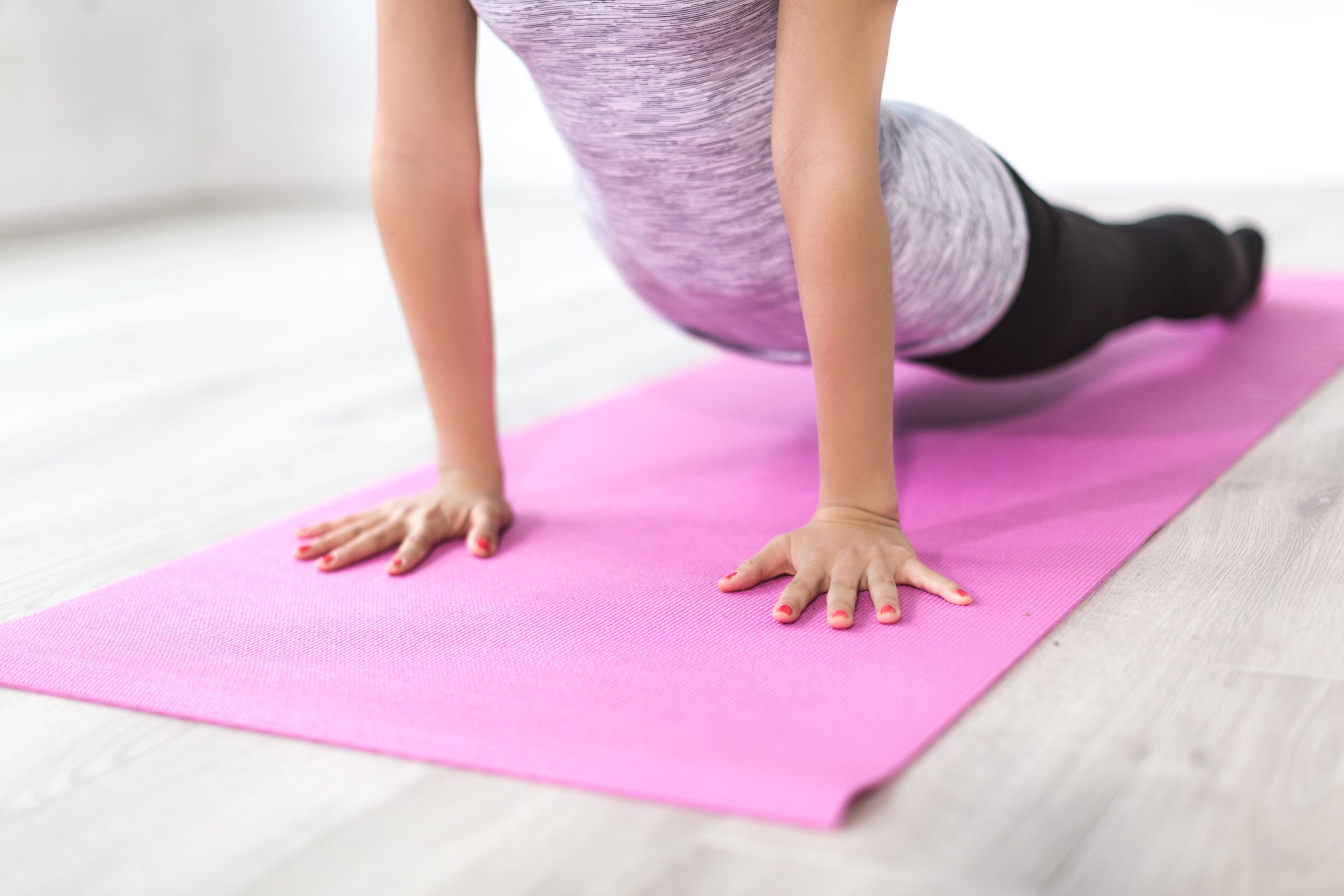 Femme réalisant un étirement de yoga sur un tapis rose